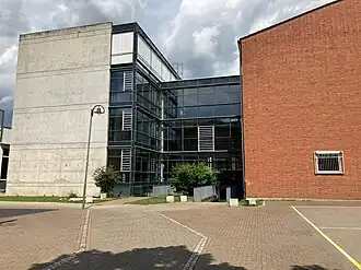 Blick auf die Schule. Links ein graues, rechts ein rotes Gebäude