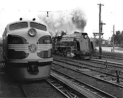 Rundnasen-Diesellokomotive steht neben einer stromlinienförmigen Dampflokomotive der S-Klasse. (Schwarzweiß-Bild)