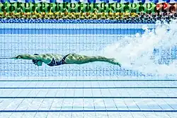 Jenna Strauch ist auf diesem Unterwasserfoto in einer Tauchphase zu sehen. Ihr Körper ist langgestreckt von den Fingerspitzen bis zu den Füßen. Sie trägt einen dunkelblauen Badeanzug und eine dunkelblaue Badekappe.