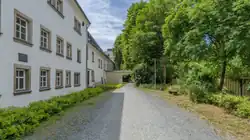 Das Foto zeigt einen geschotterten Fahrradweg. Links sieht man einen Teil des Hospitals