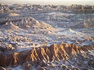 Die Cordillera de la Sal (wörtlich: Salzgebirge) ist eine Karstlandschaft aus rotem Sedimentgestein und weißem Evaporit geformt. Kochsalz und Gips lassen sie in ihren zentralen Bereichen fast wie eine Schneelandschaft aussehen.