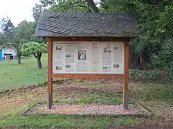 Auf der gegenüberliegenden Straßenseite ein Schaukasten: Zur Erinnerung an die Tätigkeit der Schwedin Elsa Brandström für ihr aufopferungsvolles Wirken in Bad Marienborn-Schmeckwitz