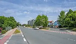 Man sieht die Schleizer Straße im Vordergrund, im Hintergrund Bushaltestelle und Wohnlandschaft; alles in Studentenberg