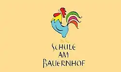 Das Logo zeigt einen bunten Hahn und den schwarzen Schriftzug „Schule am Bauernhof“ auf orangem Hintergrund.