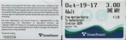 Busticket in Scheckkartenformat, Vorderseite und Rückseite nebeneinander abgebildet. Links, Rückseite, in kleiner Schrift Beförderungsbedingungen und Serviceinformationen. Rechts, Vorderseite, groß Datum Oct-19-17, Fahrpreis 3.00, Adult, One Way, kleiner From: Westlake/Seattle, To: SeaTac Airport, Directions:South. Unten Farblogo von Sound Transit mit Meereswellen.
