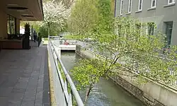 Der Seitenkanal fliesst zw. einem Supermarkt (links) und einer alten Fabrik nach hinten.