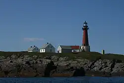 Foto eines roten Leuchtturms und einigen Nebengebäuden