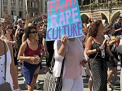 Demonstrierende Person trägt Schild mit der Aufschrift „Fight Rape Culture“.