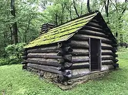 Rekonstruktion einer Holzbaracke, wie sie früher von Soldaten der Kontinentalarmee in Valley Forge bewohnt wurde. Sie ist sehr einfach gehalten, mit rechteckigem Grundriss, nur einer Tür, einem Schornstein und keinen (sichtbaren) Fenstern.