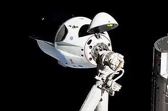 Crew Dragon im Anflug an die ISS; im Vordergrund der (nicht verwendete) Canadarm2