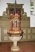 Über dem romanischen Taufbecken hängt ein Deckel von 1635, dahinter das Gestühl mit dem herzoglichen Wappen
