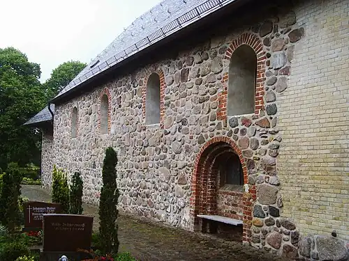 Nordseite mit romanischen Fenstern, und teilweise vermauertem ehemaligem Portal