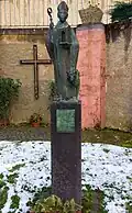 St. Remaclus mit dem Portal der Abteikirche von Stablo, Bronzestatue von Werner Franzen (2000), im alten Kirchenschiff