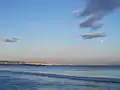 Wolken und Mond über dem Meer, am Horizont eine Küstenlinie
