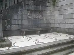 Treppenaufgang mit Musikantenrelief und Steinbank.