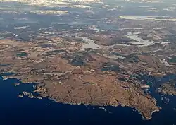 Luftbild einer an der Küste gelegenen Landschaft. Das Areal ist von Fjorden umgeben und hat mehrere Seen.