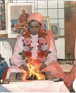 Swami Omkarananda sitzt im Schneidersitz vor einem vedischen Feuer im Jahr 1982