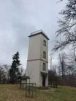 Das Landschaftsphoto zeigt zwischen Baumzweigen den Turm der Telegraphenstation 28