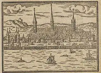 Kupferstich vom Blick auf eine Stadt mit Fluss und Segelschiffen im Vordergrund. Hinter der Stadtmauer sind viele Häuser und drei Kirchen, die von einer hügeligen Landschaft umgeben sind.