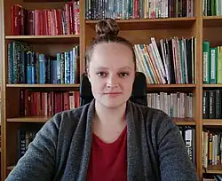 Porträt der deutschen Schriftstellerin Theresa Hannig vor einer Bücherwand, am Schreibtisch sitzend