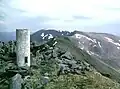 Die trigonometrische Säule auf dem Gipfel des An Socach, im Hintergrund der An Riabhachan