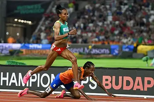 Gudaf Tsegay ziet im grünen Dress an der stürzenden Sifan Hassan in Orange vorbei.