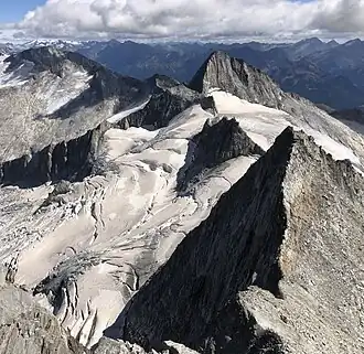 Turnerkamp mit Engländerrinne (heutiger Normalweg im Sommer) von Westen (mittig) vom Großen Möseler aus gesehen, rechts davor Östlicher Nevesferner, links vorn das Waxeggkees, direkt dahinter Rossrugggrat mit Rossruggspitze, ganz vorn der Kleine Möseler