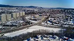 Luftbild eines städtischen Gebiets mit vielen Wohnblöcken. Im Vordergrund eine mehrspurige Straße.