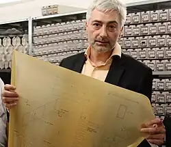 Ulrich Helbach 2011, er hält eine Planzeichnung aus seinem Archiv in den Händen