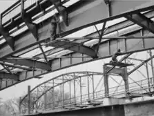 Schweißer bei der Arbeit an den Nord- und Südträgern. Die alte Brücke im Hintergrund, um den 10. Mai 1949