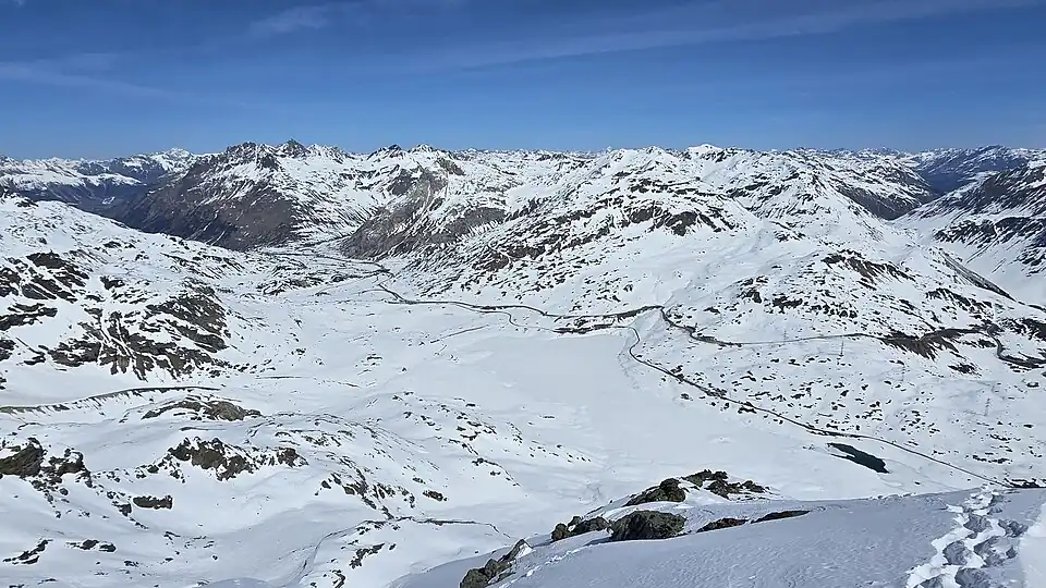 Blick nach Norden in die Val Bernina mit dem Berninapass (2235&nbsp;m), den gefrorenen Seen Lago Bianco, Lej Nair und Lej Pitschen und der Berninabahn (für Annotationen aufs Bild klicken)