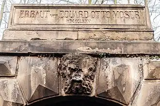 Inschriftenstein und Fratzenkopf.