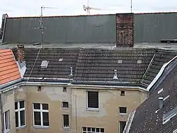 Blick vom Hof auf das Berliner Dach des Vorderhauses mit einer höher geführten vorderen Dachschräge, die einen First ausbildet