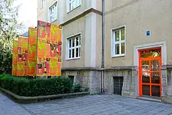 Ansicht der Goethestraße 54 als Interimsquartier der Villa Stuck, mit orange gestrichener Tür und bunten Fahnen