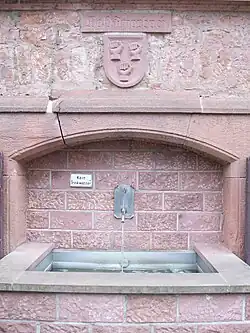 Der Dorfbrunnen im Ortszentrum mit dem Wappen der Schelle von Amorbach