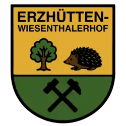 Das Wappen zeigt einen Baum, einen Igel sowie Schlägel und Eisen. Der Baum steht für die Napoleon-Eiche, ein Naturdenkmal in Erzhütten-Wiesenthalerhof. Baum und Igel symbolisieren den Pfälzerwald, welcher den Ort umgibt. Schlägel und Eisen stehen für den einstmals erfolgten Eisenerzabbau. Über den Symbolbildern steht "ERZHÜTTEN-WIESENTHALERHOF" geschrieben. Das Wappen ist farblich in zwei Hälften geteilt, getrennt durch einen schwarzen Strich. Baum und Igel befinden sich in der oberen Hälfte vor einem gelben Hintergrund, Schlägel und Eisen im unteren Teil vor einem grünen Hintergrund.