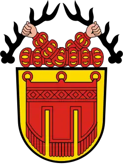 mit geschlitzten Puffärmeln bekleidete Männerarme, die zwei mit Spitzen aufwärts zeigende Hirschstangen halten