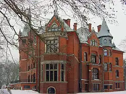 Panoramablick auf das in roter Fassade sichtbare und modern wirkende Schlossgebäude.