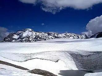Plaine-Morte-Gletscher am rechten Bildrand östlich des Wildstrubels, erkennbar am felsigen, steilen Südabhang, über dem sich Wolken auftürmen – rechts vom Einschnitt der Nordhang von Les Faverges