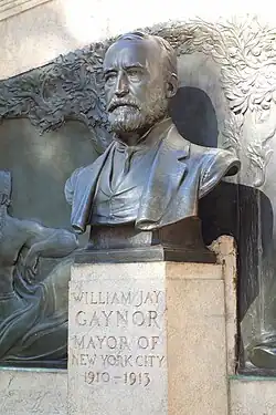 Bronze-Büste auf Granit-Stele vor Bronze-Tiefrelief. Inschrift: WILLIAM JAY / GAYNOR / MAYOR OF / NEW YORK CITY / 1910–1913