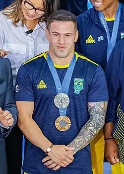 Lima trägt ein dunkelblaues Trikot, an blauen Bändern um den Hals trägt er Silber und Bronze.