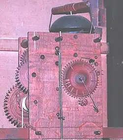 Hölzernes Bodenstanduhrwerk, Schlossscheibe mit relativ tiefen Lücken, z.&nbsp;Zt. der Aufnahme wird 11 Uhr geschlagen