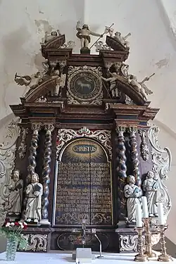 Im Mittelfeld des Altarretabels der Willehadi-Kirche von Wremen von 1709 sind die Einsetzungsworte des Abendmahls zu lesen, gerahmt je zwei gewundenen Säulen und je zwei Evangelistenfiguren. Unter dem Text Darstellung des Abendmahls, darüber das Lamm Gottes, gerahmt von Moses und Johannes dem Täufer; auferstandener Christus als Krönung.