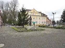 Zbąszynek Bahnhofsvorplatz. Die Heilige Katharina von Alexandrien ist Schutzheilige der Eisenbahner. Das Rad verweist auf ihr Martyrium.