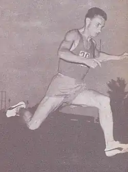 Jüngerer Mann im Sporttrikot in seitlicher Aufnahme nach rechts schauend in einer Laufbewegung befindlich und in schwarzweiß.