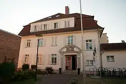 Zu sehen ist ein zweistöckiges Haus, erkennbar sind zahlreiche Anbauten.