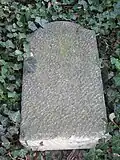 Privater Grabstein auf dem Massengrab, umgestürzt
