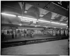 U-Bahnhof 96th Street um 1970 in einem Übergangsstadium mit Glühlampen und Leuchtstofflampen, mit noch weißem Unimark-Liniensignet auf schwarzem Stationsschild, mit noch nicht abgesperrtem oder vermauertem Seitenbahnsteig