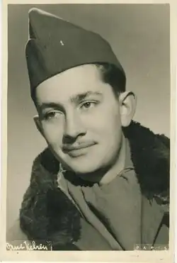 Das Bild zeigt den französischen Sänger und Schauspieler Jean-Claude Pascal. Das Bild stammt aus dem Jahr 1945 und ist in ein in gelblich-bräunlich gehalten. Pascal trägt eine Mütze und eine Jacke mit Fellkragen.